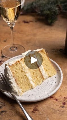 a piece of cake sitting on top of a white plate next to a glass of wine