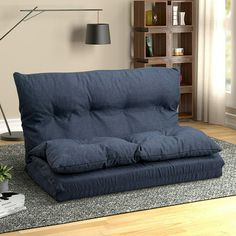 a blue futon sofa sitting on top of a rug in front of a window