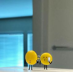 two little yellow smiley faces are standing next to each other in front of a mirror