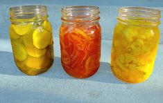 three jars filled with pickles and lemons