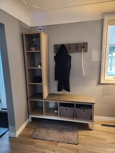 a coat rack with two bins and some clothes hanging on the wall next to it