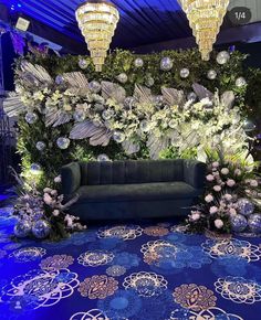 a couch sitting on top of a blue carpet next to chandeliers and flowers