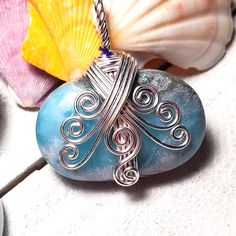 a blue bead sitting on top of a piece of glass next to seashells