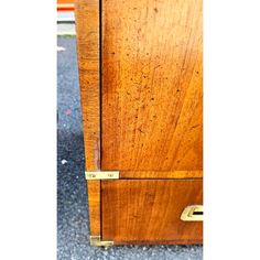 an old wooden cabinet with brass handles on the door and bottom drawer is missing it's handle