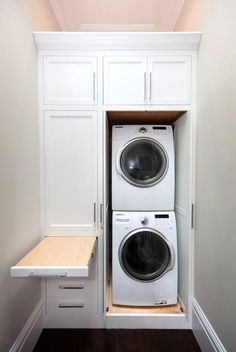 a white washer and dryer in a small room with built - in cabinets