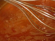 the whisks are being stirred in an orange sauce