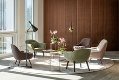 a living room filled with lots of furniture and large windows next to a wooden wall