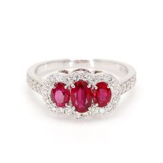 Classic ruby 3-stone ring in 14 karat white gold. This ring is prong set with three 1.30cttw red oval shaped ruby corundum, and 42 diamonds weighing 0.52cttw. Ring Size 7. Ruby Is The Birth Stone For July. Classic Red Three Stone Rings, Red Three Stone Diamond Ring For Promise, Red Three Stone Diamond Promise Ring, Oval Ruby Ring With Three Diamonds, Oval Three Stone Ruby Ring With Diamonds, Classic Red Three Stone Diamond Ring, Red Three-stone Diamond Promise Ring, Classic Red Three-stone Ring, Red Three Stone Round Cut Ruby Ring