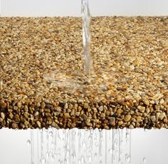 water pouring from a faucet on top of a rock covered surface with rocks and pebbles