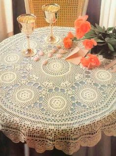 a lace tablecloth with roses on it and two goblets sitting on the table