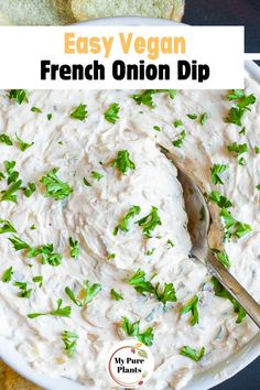 a white bowl filled with ranch dip and topped with parsley on top, next to a piece of bread