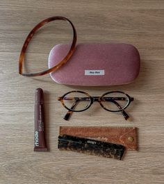 a pair of glasses sitting on top of a wooden table next to a pink case