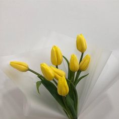 a bouquet of yellow tulips sitting on top of a white sheet