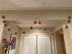 some lights are hanging from the ceiling in a room with white shutters and pink flowers