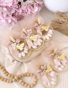 three pairs of pink and gold earrings with butterflies on them next to some beads, flowers and a beaded necklace