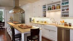 a large kitchen with white cabinets and wooden flooring, along with an island in the middle