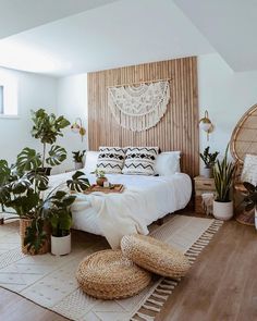 a bedroom with white bedding and lots of plants in baskets on the rugs