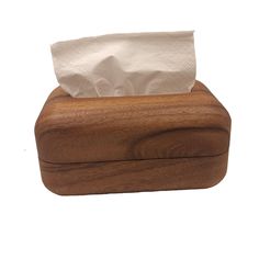 a tissue dispenser made out of wood with a white paper towel in it