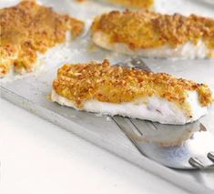 some fish fillets are sitting on a plate with a fork and spoon next to it