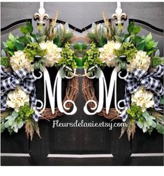 the monogrammed wreath is decorated with white and green flowers, greenery, and leaves