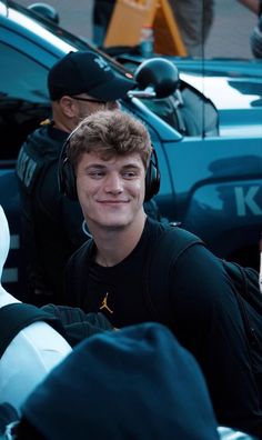 a young man wearing headphones sitting in the back of a truck next to police officers