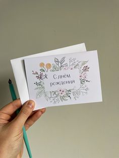 a person holding up a card with flowers on it