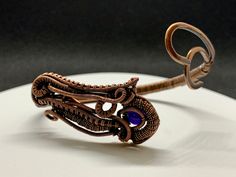 Hand woven copper coils and curves around a heavy gauge hammered copper frame with an amethyst bead accent. Approximately 6 3/4' adjustable to the wrist. Based on a Nicole Hanna Design. This bracelet has been antiqued, polished and sealed. Sealed with Protectaclear. ProtectaClear is a clear, protective coating that is tough enough to protect jewelry and is safe for wear against skin. ProtectaClear is practically invisible once applied and will seal and protect jewelry from tarnish, oxidation, an Adjustable Wire Wrapped Bronze Cuff Bracelet, Hanna Design, Coil Bracelet, Copper Frame, Amethyst Bracelet, Amethyst Beads, Hammered Copper, Coils, Hand Woven