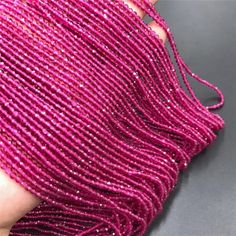 the pink beaded fabric is being held by someone's hand