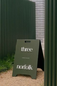 there is a sign that says three in front of a building with green sidings