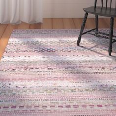 a wooden chair sitting on top of a floor next to a rug covered in multicolored squares