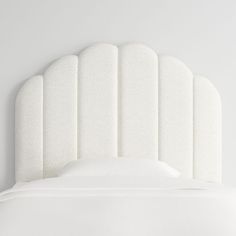 an upholstered white headboard on a bed with no sheets or pillows in it