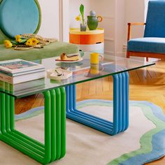 a living room filled with furniture and a glass top table in front of a blue chair