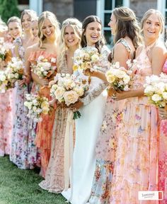 a group of women standing next to each other holding bouquets in their hands and smiling