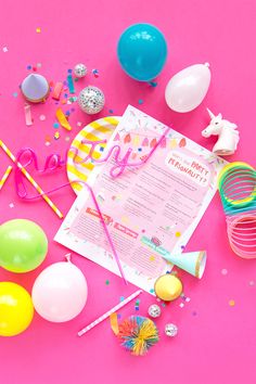 a pink table topped with lots of balloons and confetti next to a paper