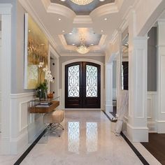 an elegant entry way with marble flooring and chandelier above the doorways