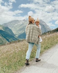 a woman walking down a dirt road in the mountains