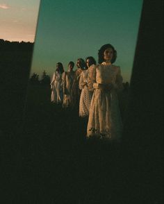 a group of women standing next to each other in front of a forest at night