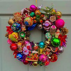 a colorful christmas ornament wreath hanging on a door with ornaments all over it