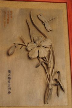 a plaque with some flowers on it and chinese writing in the bottom right hand corner