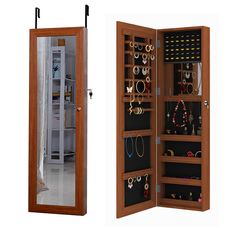 an open wooden jewelry cabinet next to a mirror