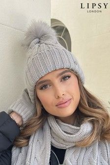 a woman wearing a gray hat and scarf with a pom - pom on it