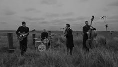 three men are playing instruments in the grass