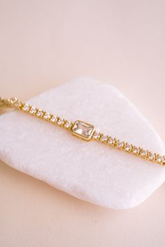 Meet your new favorite accessory: the Amelia Brilliant Cut Tennis Bracelet! We love how it effortlessly adds sparkle to your everyday look, whether you're dressing up for a date night or just want to feel a bit more glam. With its row of dazzling stones and eye-catching emerald cut center, all set in delicate 14k gold plating, this bracelet makes every outfit feel a little more special. The perfect blend of chic and sophisticated, the Amelia Bracelet lets you shine in your own unique way.BRACELE Elegant Adjustable Jewelry With Handset Stones, Luxury Adjustable Crystal Diamond Bracelet, Adjustable Sparkling Tennis Bracelet Gift, Glamorous Adjustable Bracelet As Gift, Adjustable Bling Tennis Bracelet Gift, Elegant Crystal Tennis Bracelet With Bling, Glamorous Diamond Bracelet For Gift, Elegant Rhinestone Tennis Bracelet For Party, Glamorous Sparkling Cubic Zirconia Crystal Bracelet