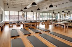 an empty gym with rows of yoga mats on the floor and tables in front of them