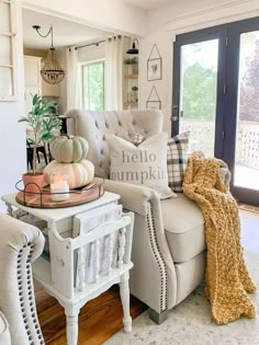 a living room filled with furniture next to a window covered in fall decorations and pumpkins