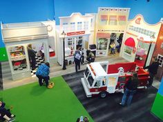 people are looking at toys on display in a toy store with green carpet and blue walls