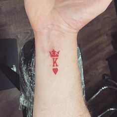 a person with a red heart and crown tattoo on their wrist