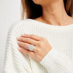 a woman wearing a white sweater and diamond ring