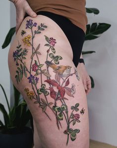 a woman's thigh with flowers and birds on it