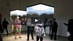 a group of people standing around in front of some glass walls with mirrors on them